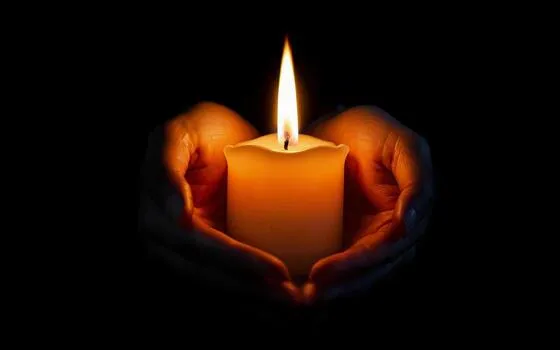 holding-a-burning-candle-in-his-hands-on-a-black-background-photo